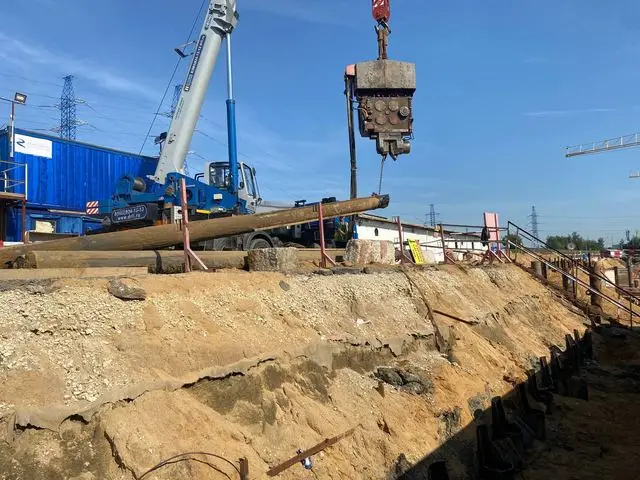 Шпунтовая стенка вдоль откоса и автокран с вибропогружателем