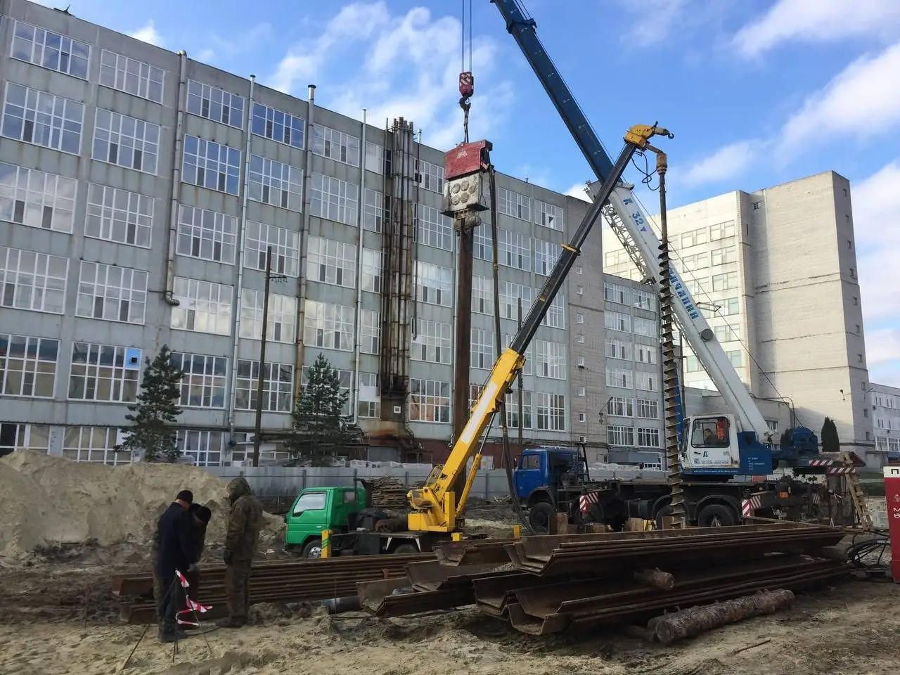 Буровая установка и автокран у здания