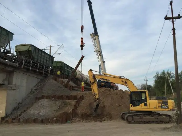 Экскаватор у шпунтового ограждения под железнодорожным мостом